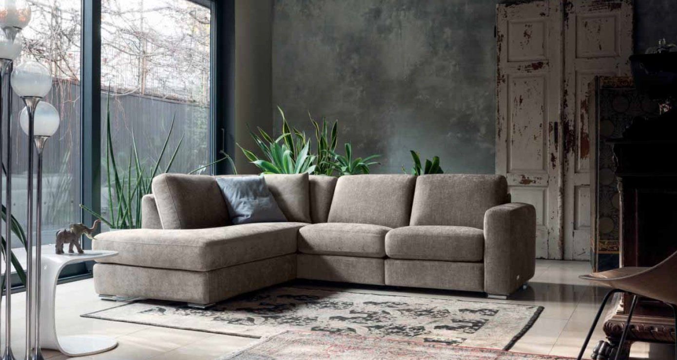 Divano componibile beige in un soggiorno moderno con tappeto e piante.