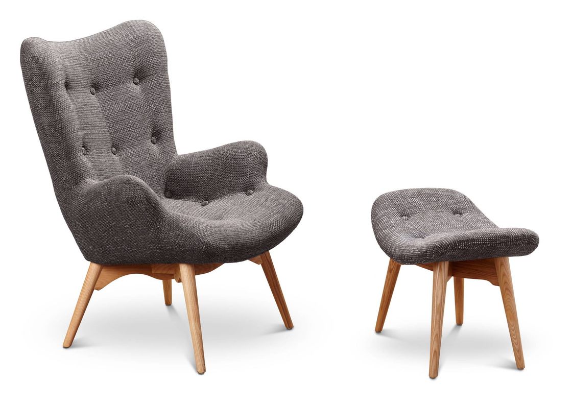 Poltrona imbottita grigia con pouf coordinato, gambe in legno, su sfondo bianco.
