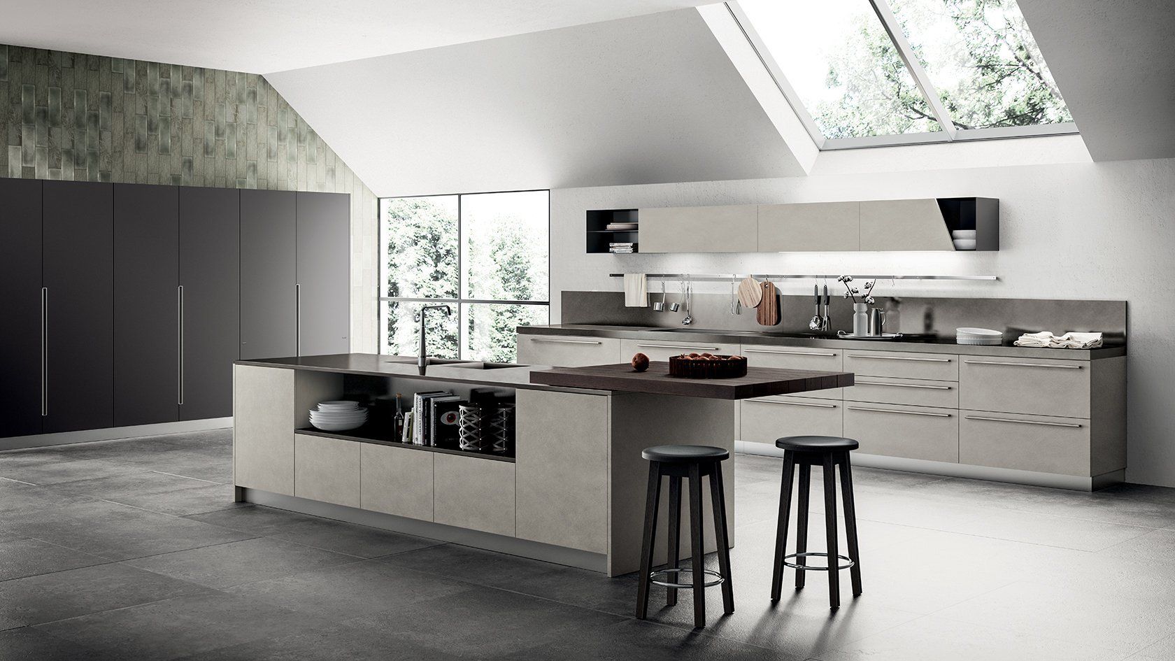 Cucina moderna con mobili chiari, isola e due sgabelli. Finestra e lucernario illuminano lo spazio.