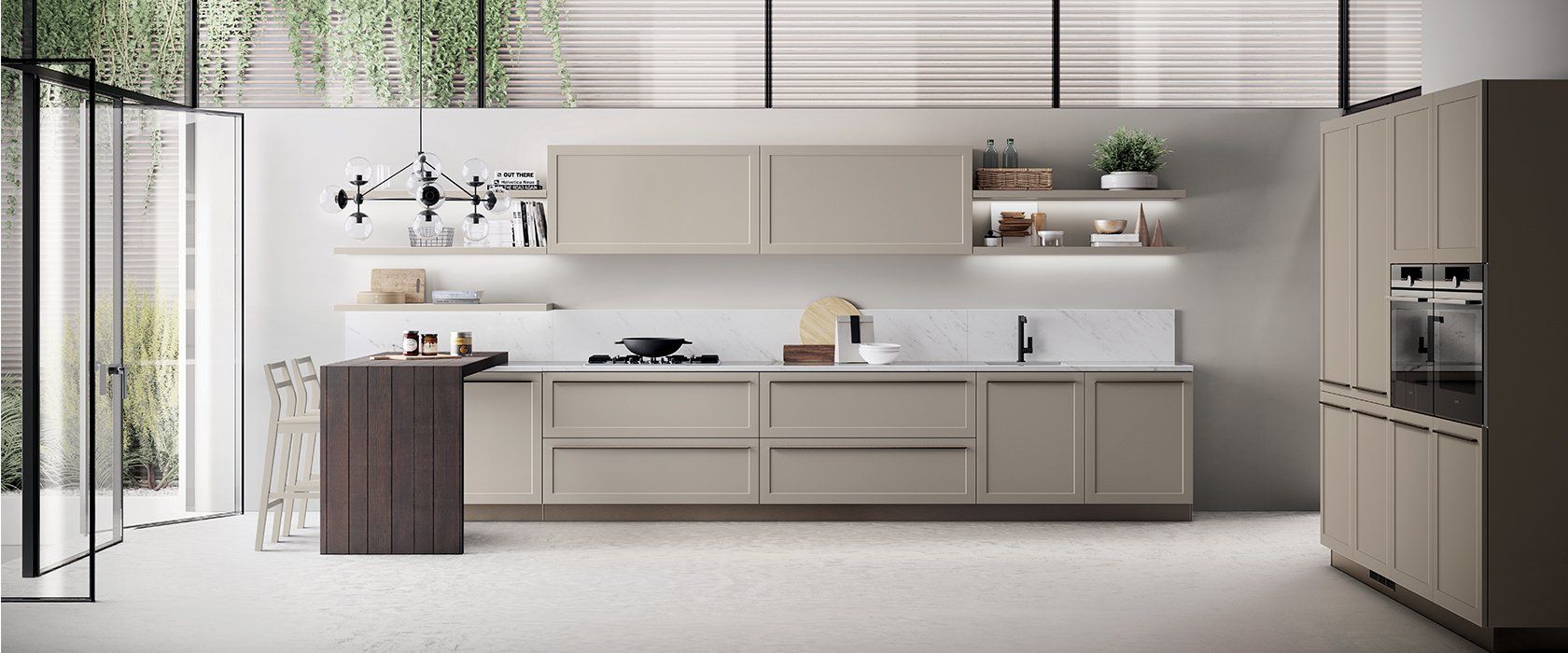 Cucina moderna con mobili beige chiaro, un'isola scura e una porta a vetri che si affaccia sul giardino.
