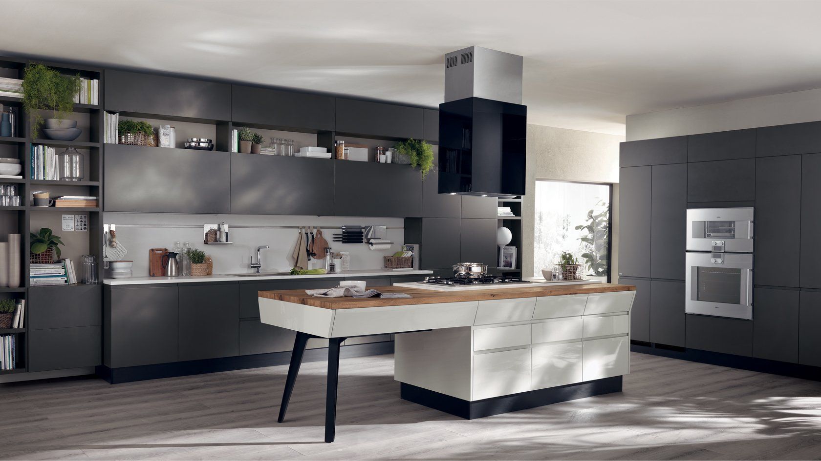 Cucina moderna con mobili grigio scuro, isola in legno, elettrodomestici in acciaio inossidabile e piante.