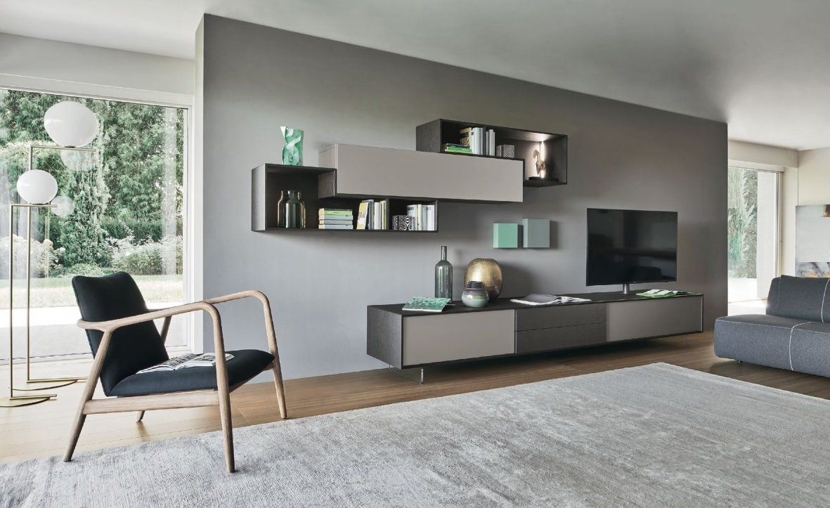 Soggiorno moderno con parete decorativa grigia, mensole sospese, TV e mobili.