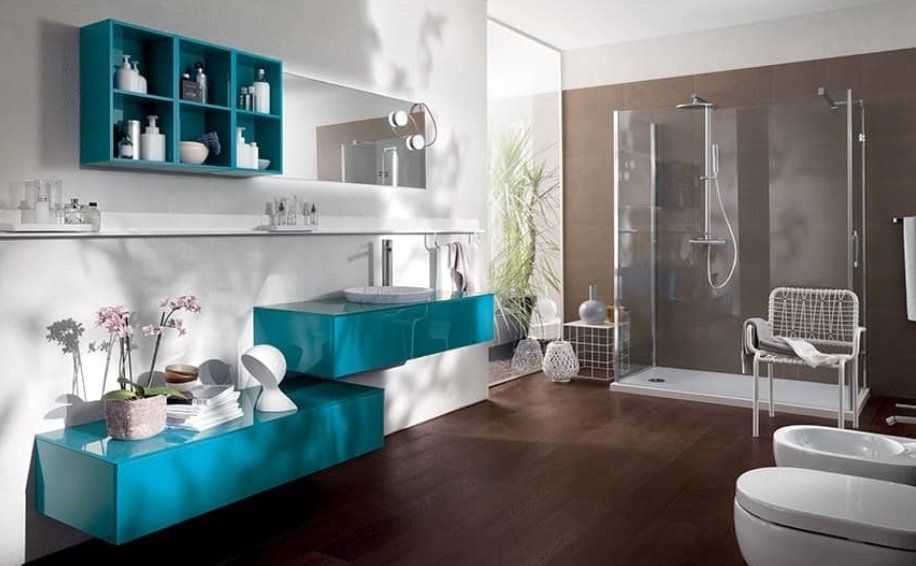 Bagno moderno con mobili color verde acqua, doccia e WC bianco, pavimento scuro.