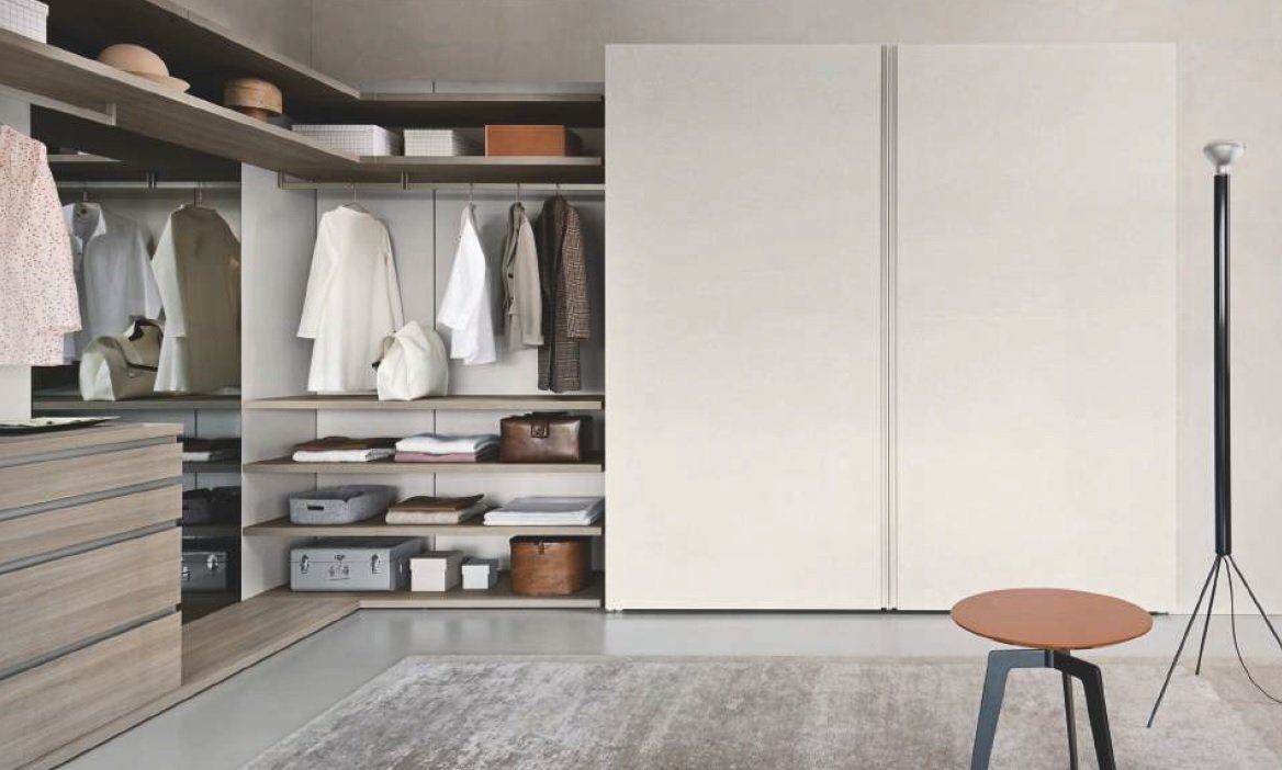 Cabina armadio con ripiani a vista, appendiabiti e ante bianche chiuse. Combinazione di colori beige e bianco.