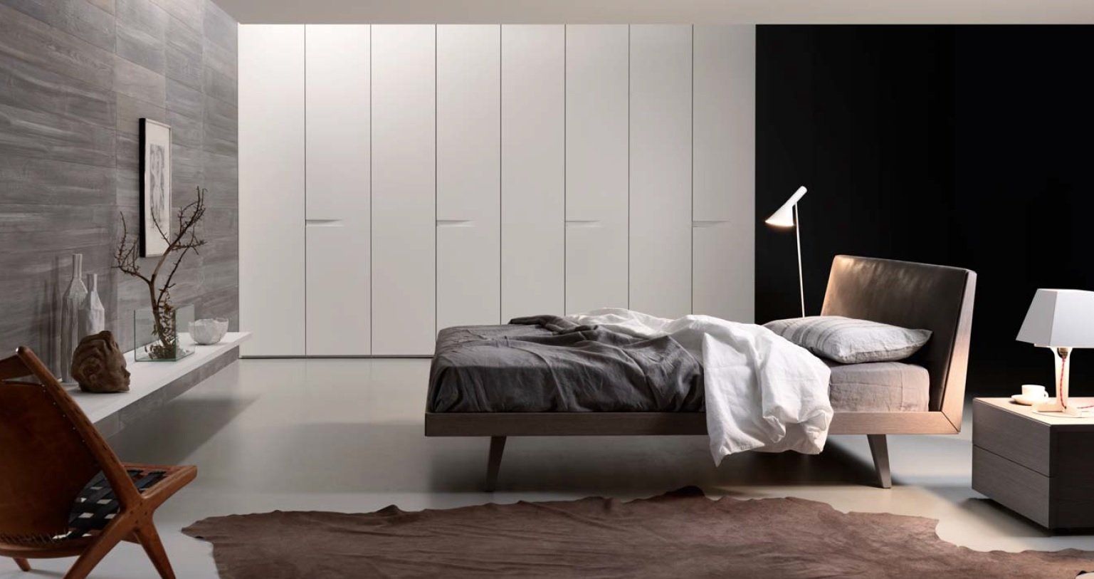Camera da letto moderna con letto, grande armadio bianco e oggetti decorativi.