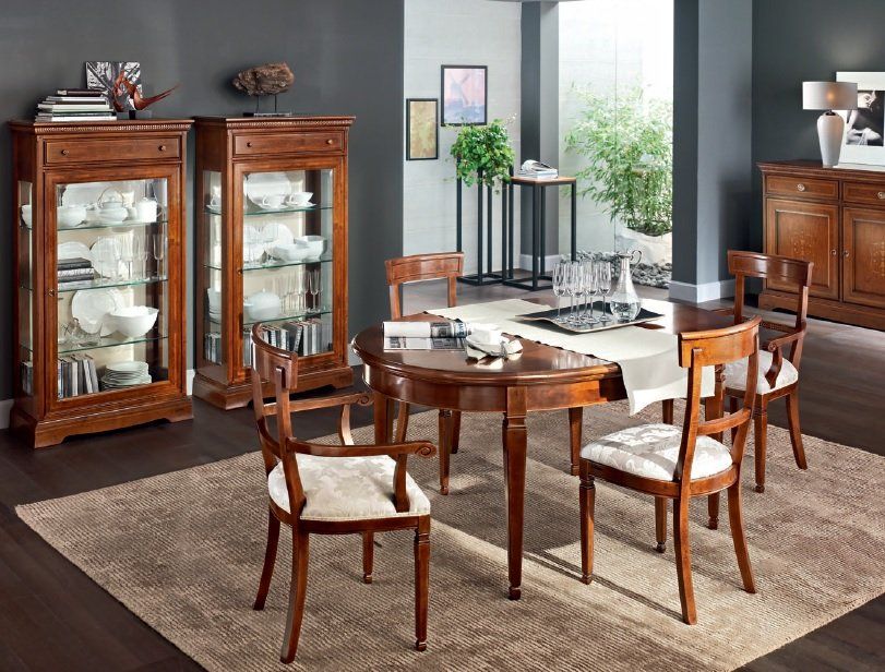 Sala da pranzo con mobili in legno: tavolo, sedie, armadi; tappeto sul pavimento; luce solare.