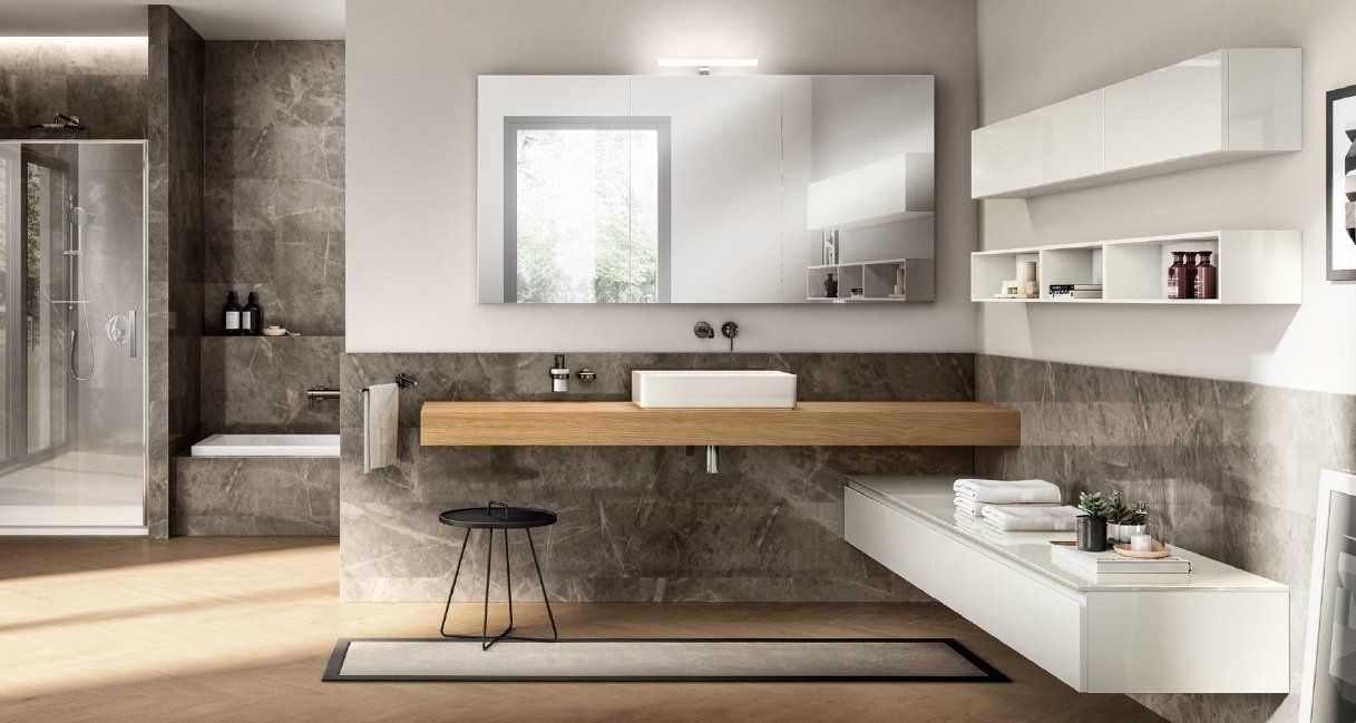 Bagno moderno con dettagli in legno e grigio: mobile lavabo sospeso, grande specchio, doccia e spazio per riporre gli oggetti.