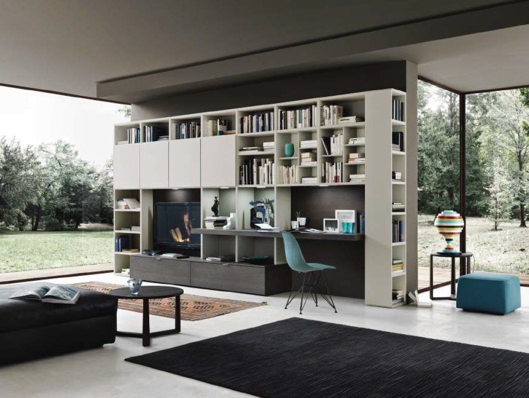Soggiorno moderno con scaffali integrati, scrivania e TV, con vista sul verde.