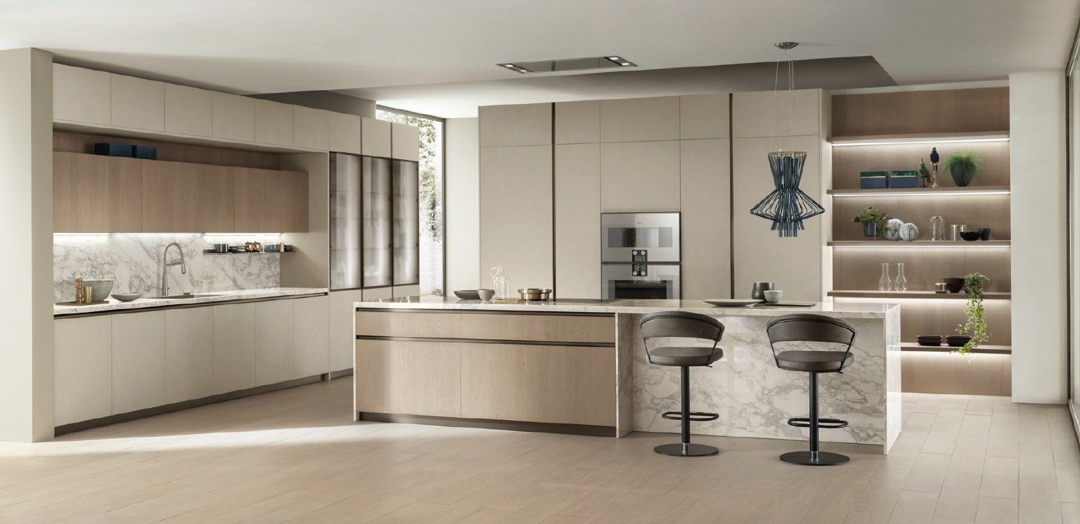 Cucina moderna e minimalista con mobili in legno chiaro, un'isola centrale e due sgabelli da bar.