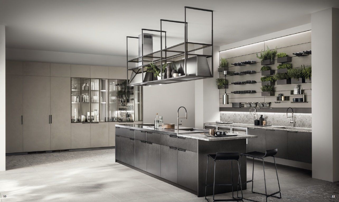 Cucina moderna con isola in acciaio inox, mensole sospese e una parete di piante.