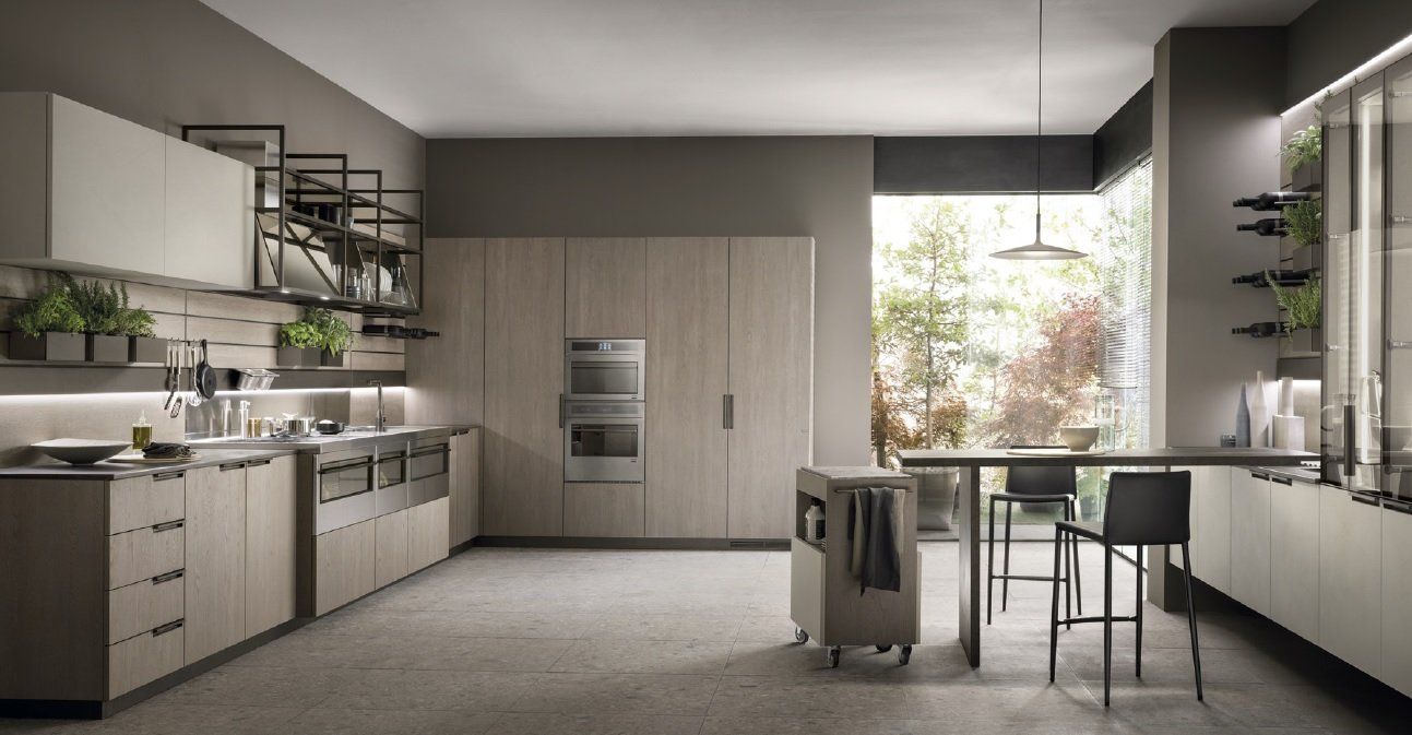 Cucina moderna con mobili in legno chiaro, dettagli in acciaio inossidabile e ampie finestre con vista sul giardino.