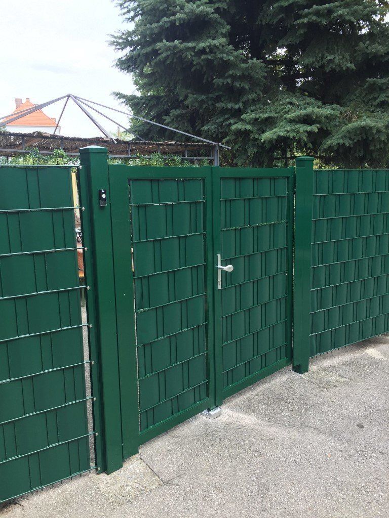 Ein grüner Zaun mit einem Tor in der Mitte