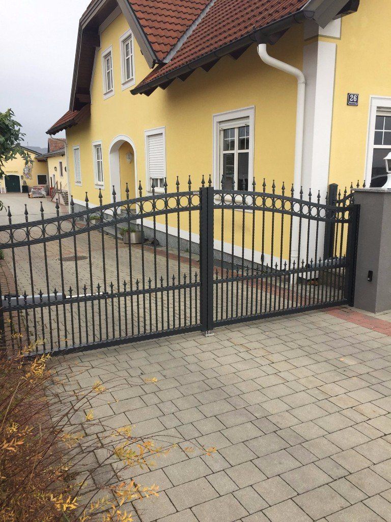 Ein gelbes Haus mit einem schwarzen Tor davor