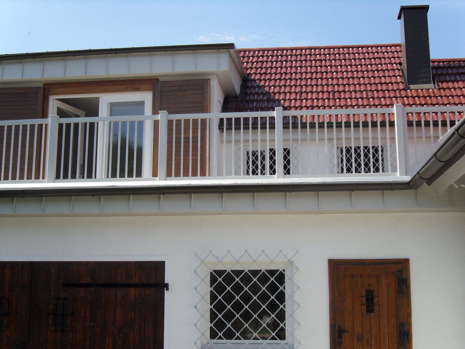 Ein weißes Haus mit Balkon und rotem Ziegeldach