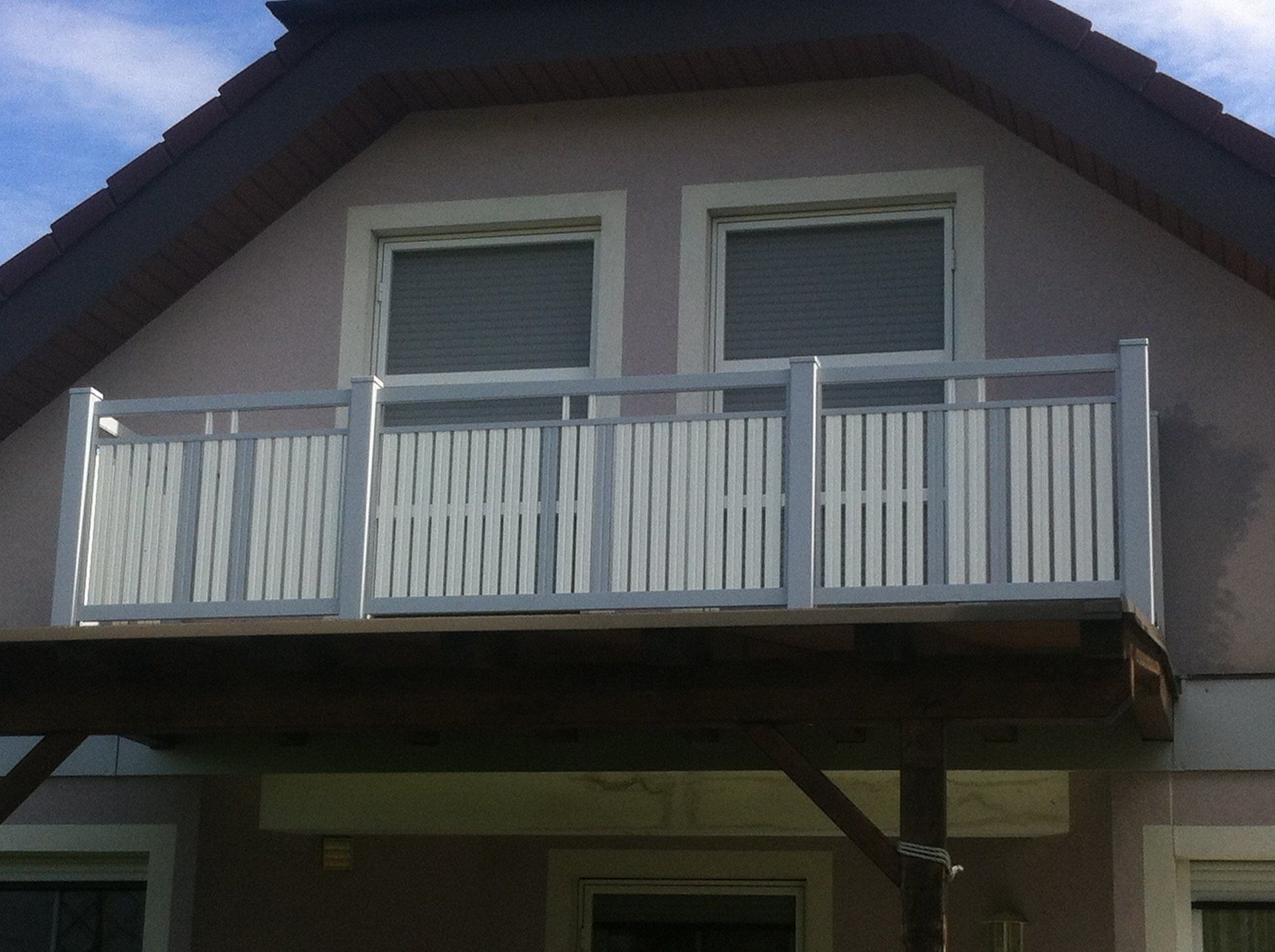 Ein Balkon mit einem weißen Geländer an der Seite eines Hauses