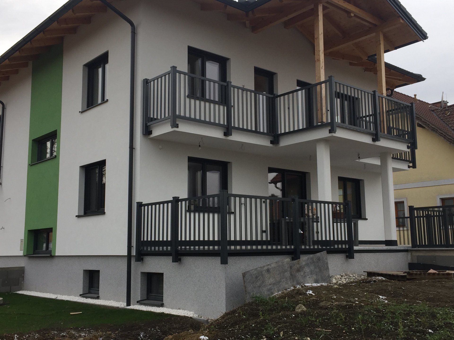 Ein weiß-grünes Haus mit einem Balkon im zweiten Stock