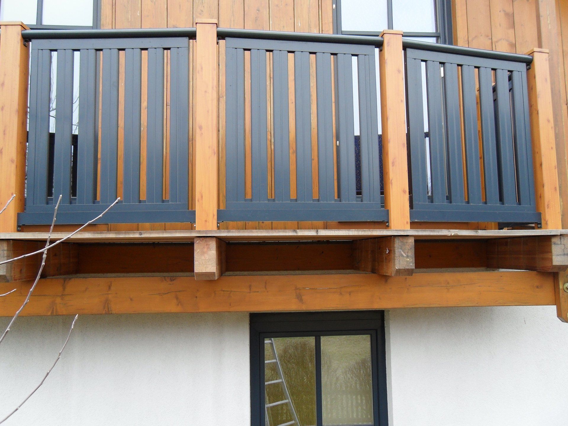 Ein Holzbalkon mit schwarzem Geländer an der Seite eines Hauses