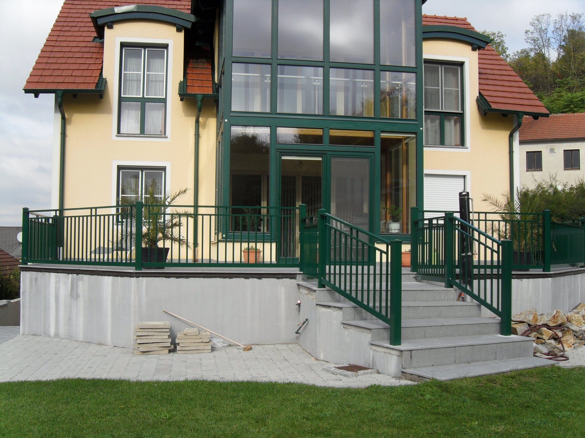 Ein gelbes Haus mit einem grünen Geländer und Treppen