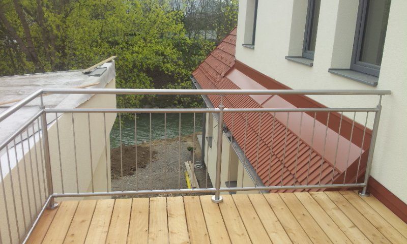 Ein Balkon mit Edelstahlgeländer und Holzterrasse