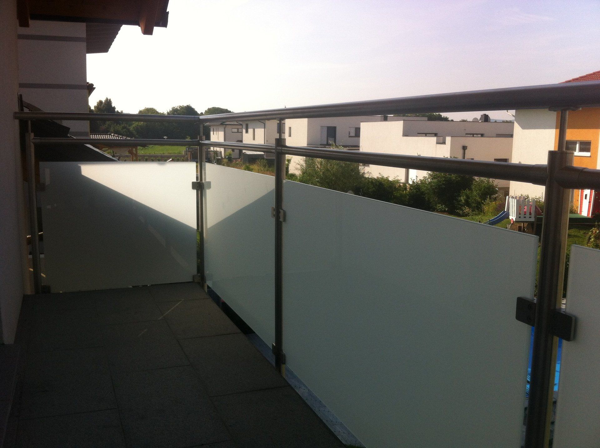 Ein Balkon mit Edelstahlgeländer und Milchglas