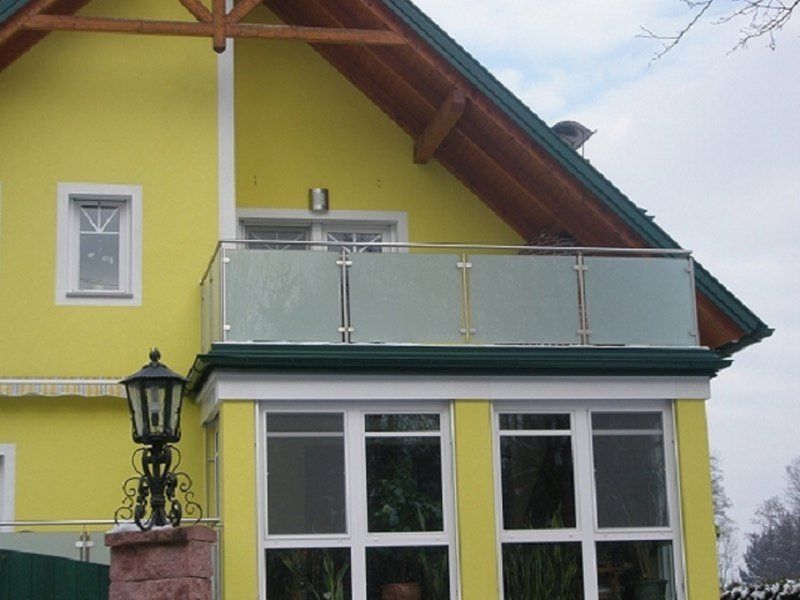 Ein gelbes Haus mit einem Balkon und einem Laternenpfahl