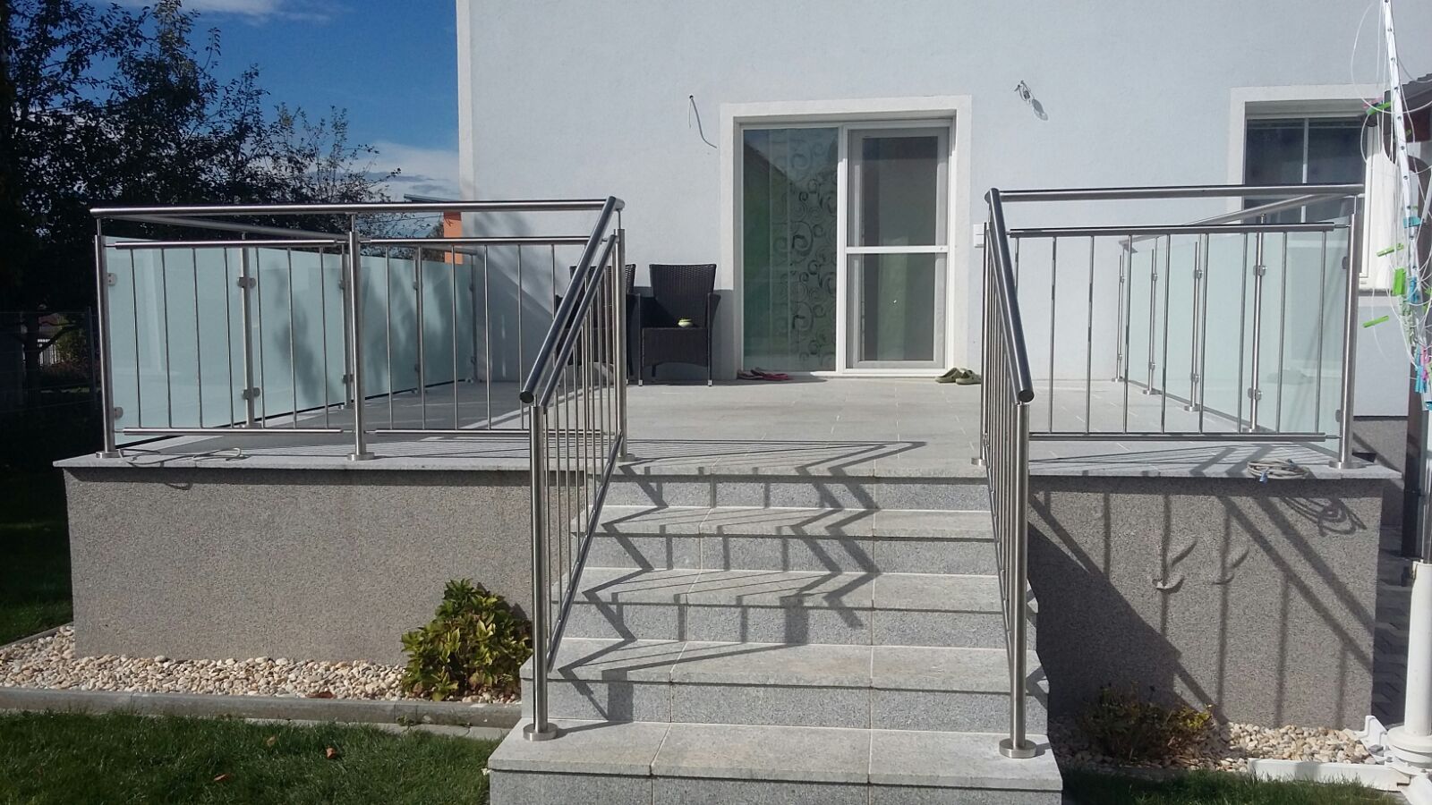 Ein weißes Haus mit einem Edelstahlgeländer und einer Treppe, die dorthin führt.