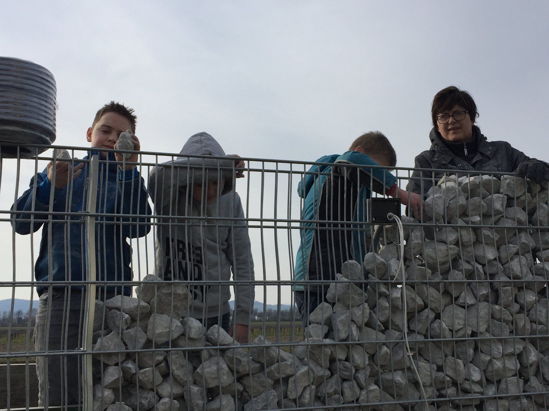 Eine Gruppe von Leuten steht hinter einem Zaun mit Steinen.