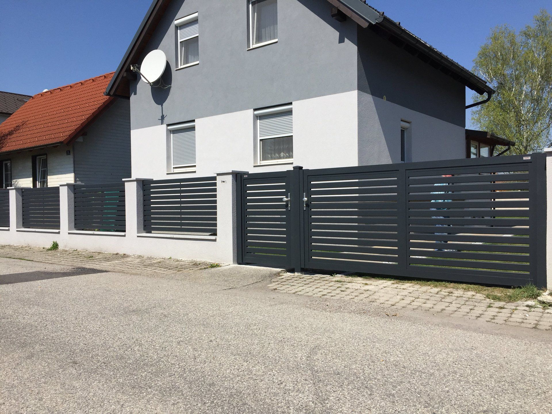 Ein Haus mit einem Zaun darum und einer Satellitenschüssel auf dem Dach.
