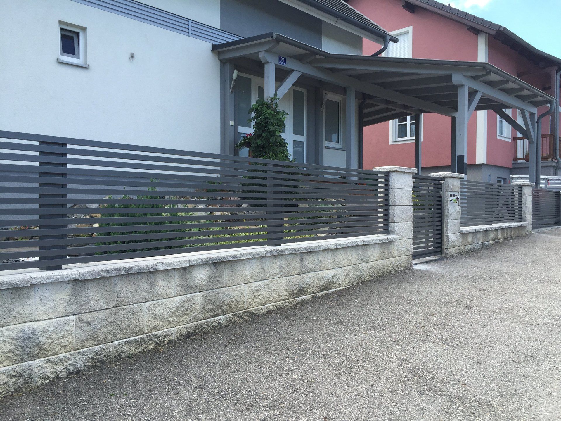 Ein Haus mit einem Zaun und einer Veranda davor