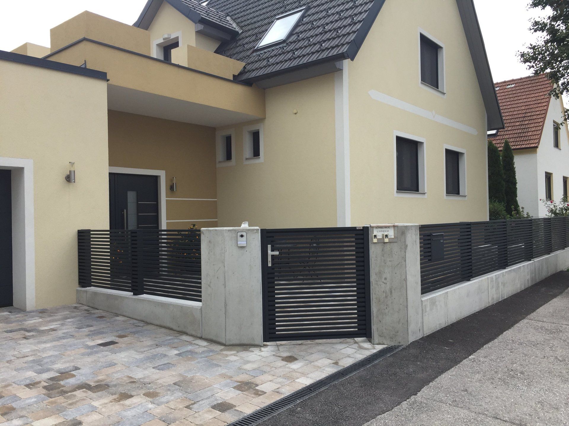 Ein Haus mit einem schwarzen Zaun und einer schwarzen Tür