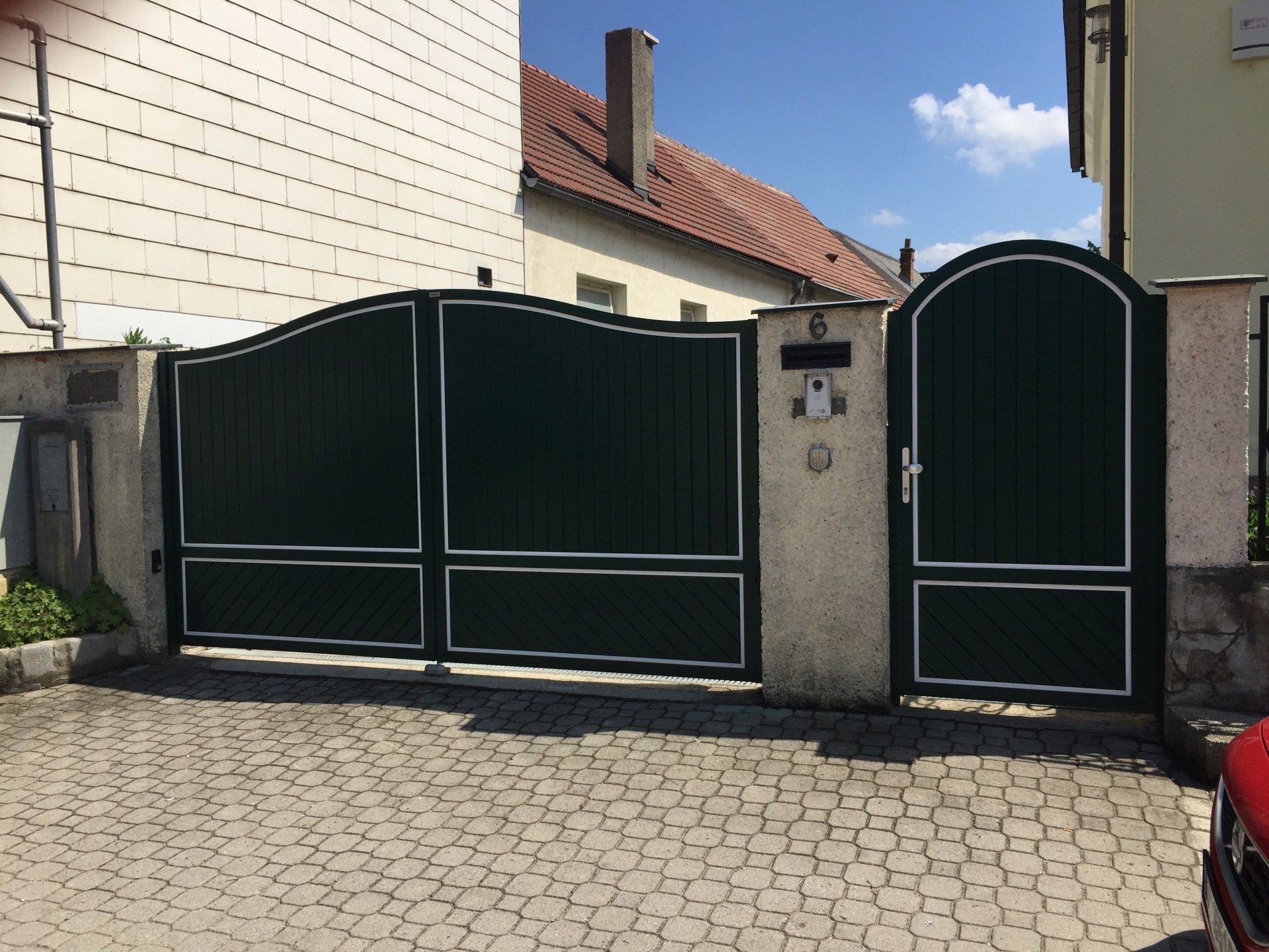 Ein Auto steht vor einem Haus mit einem grünen Tor