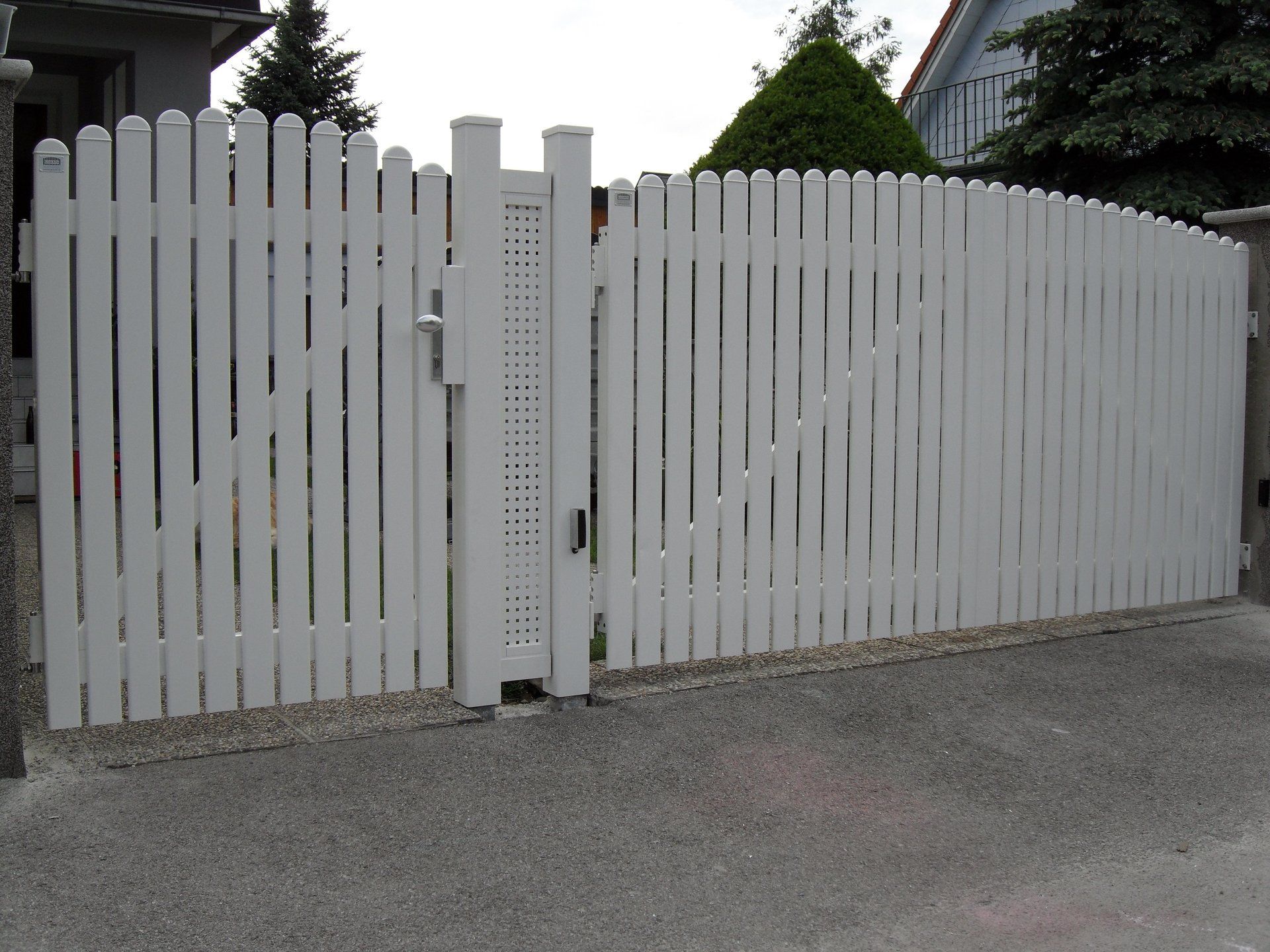 Ein weißer Lattenzaun mit einem Tor vor einem Haus