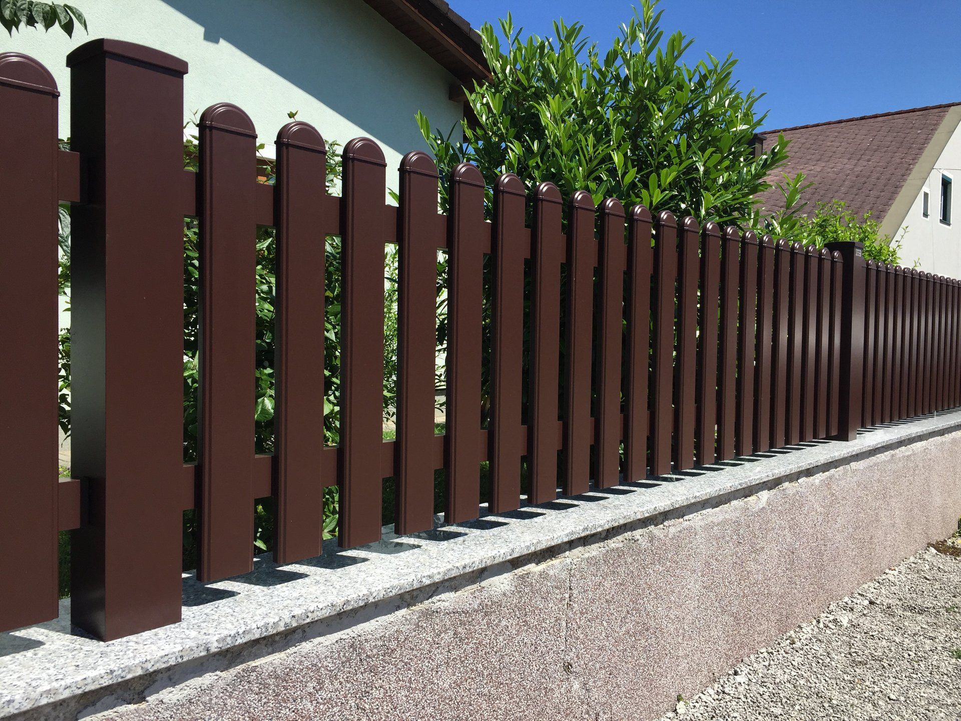 Ein brauner Holzzaun mit einem Haus im Hintergrund