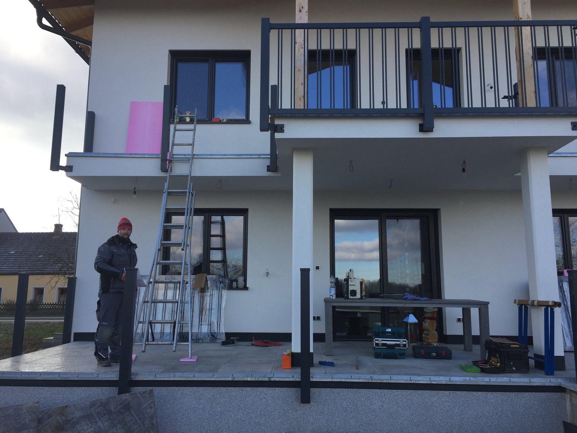 Ein Mann steht vor einem weißen Haus mit Balkon.