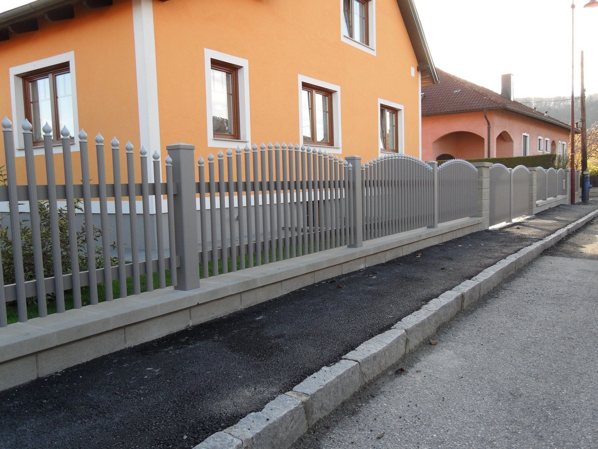 Ein orangefarbenes Haus mit einem Zaun davor