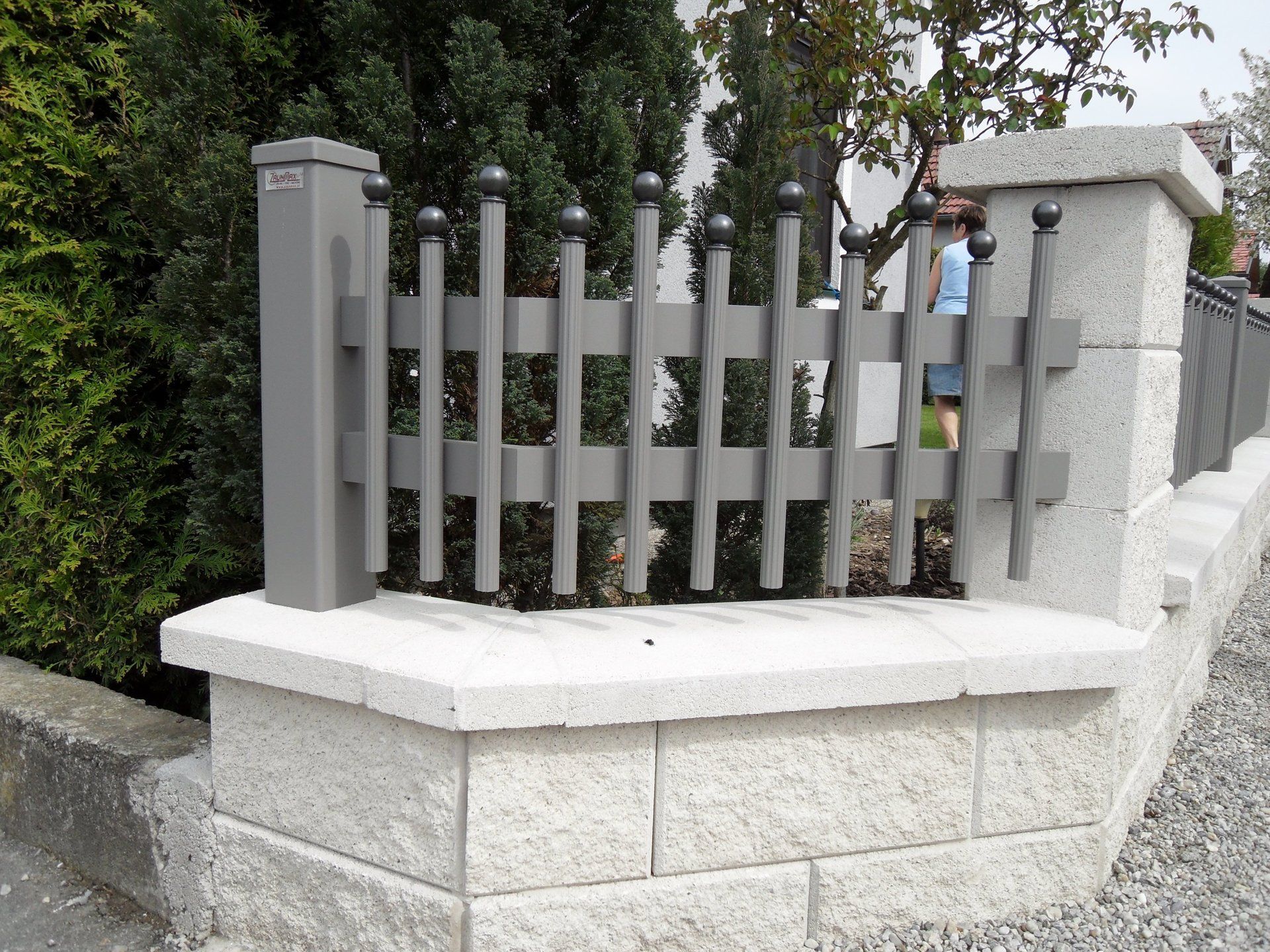 Ein grauer Zaun sitzt auf einer Steinmauer