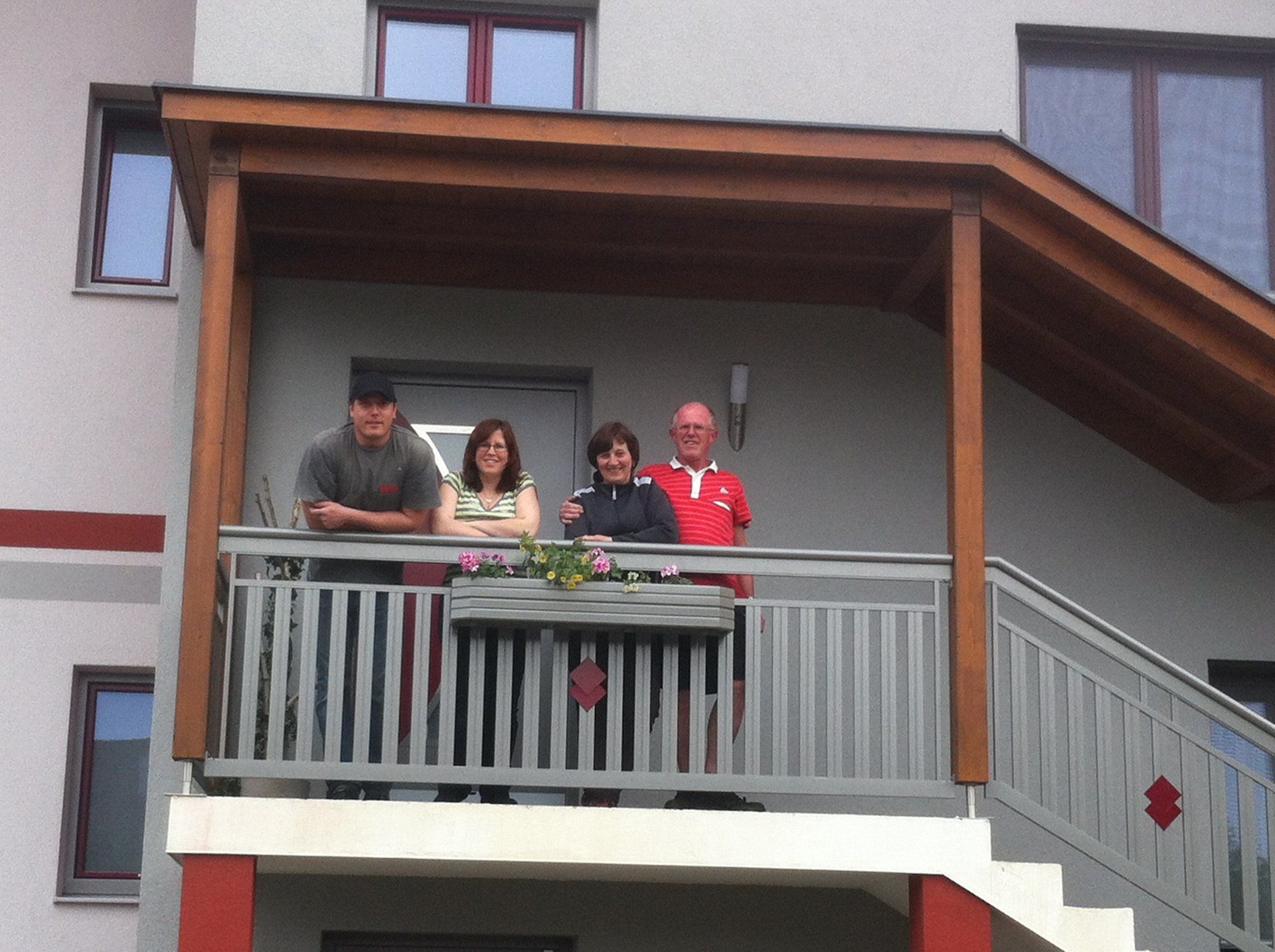 Eine Gruppe von Menschen steht auf einem Balkon vor einem Haus