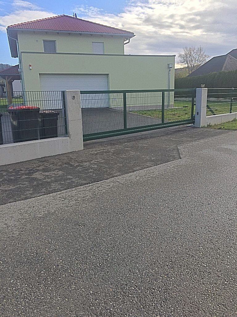 Ein Haus mit Schiebetor und davor liegender Auffahrt.