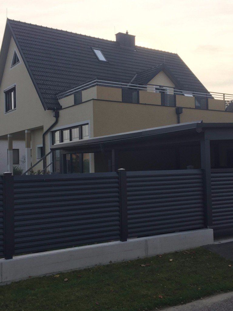 Ein großes Haus mit einem schwarzen Zaun davor.