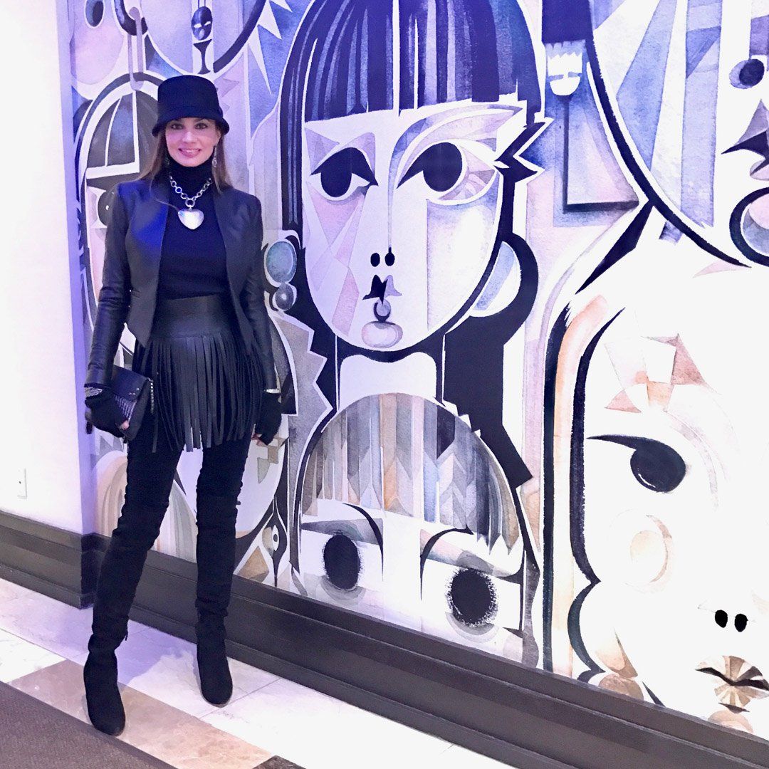 A woman is standing in front of a painting of a woman 's face.