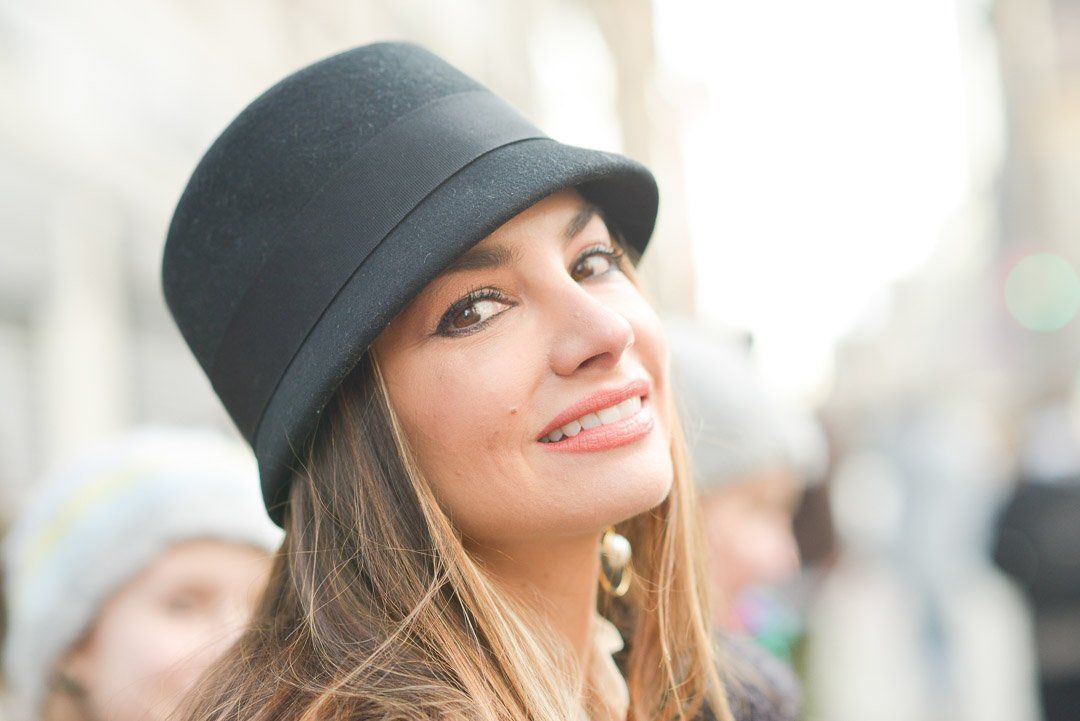 A woman is wearing a black hat and smiling.
