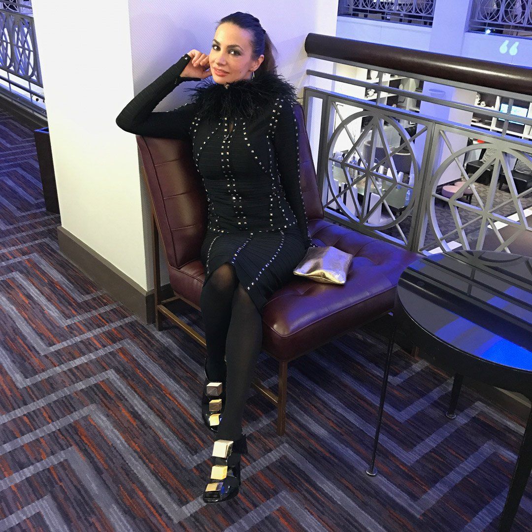 A woman in a black dress is sitting on a chair.