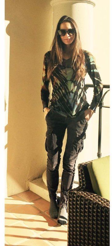 A woman wearing sunglasses is standing next to a chair.