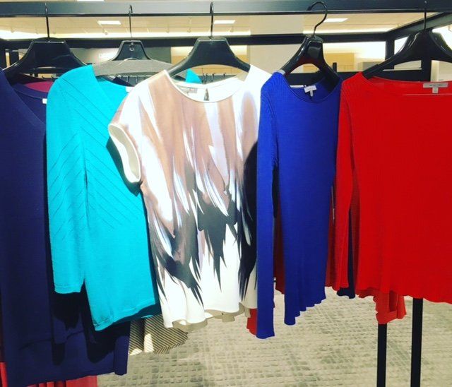 A row of colorful shirts are hanging on a rack