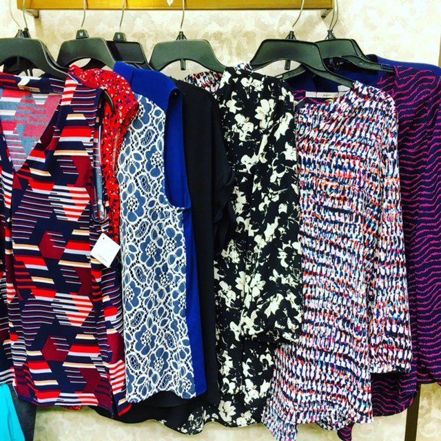 A row of colorful shirts are hanging on a rack