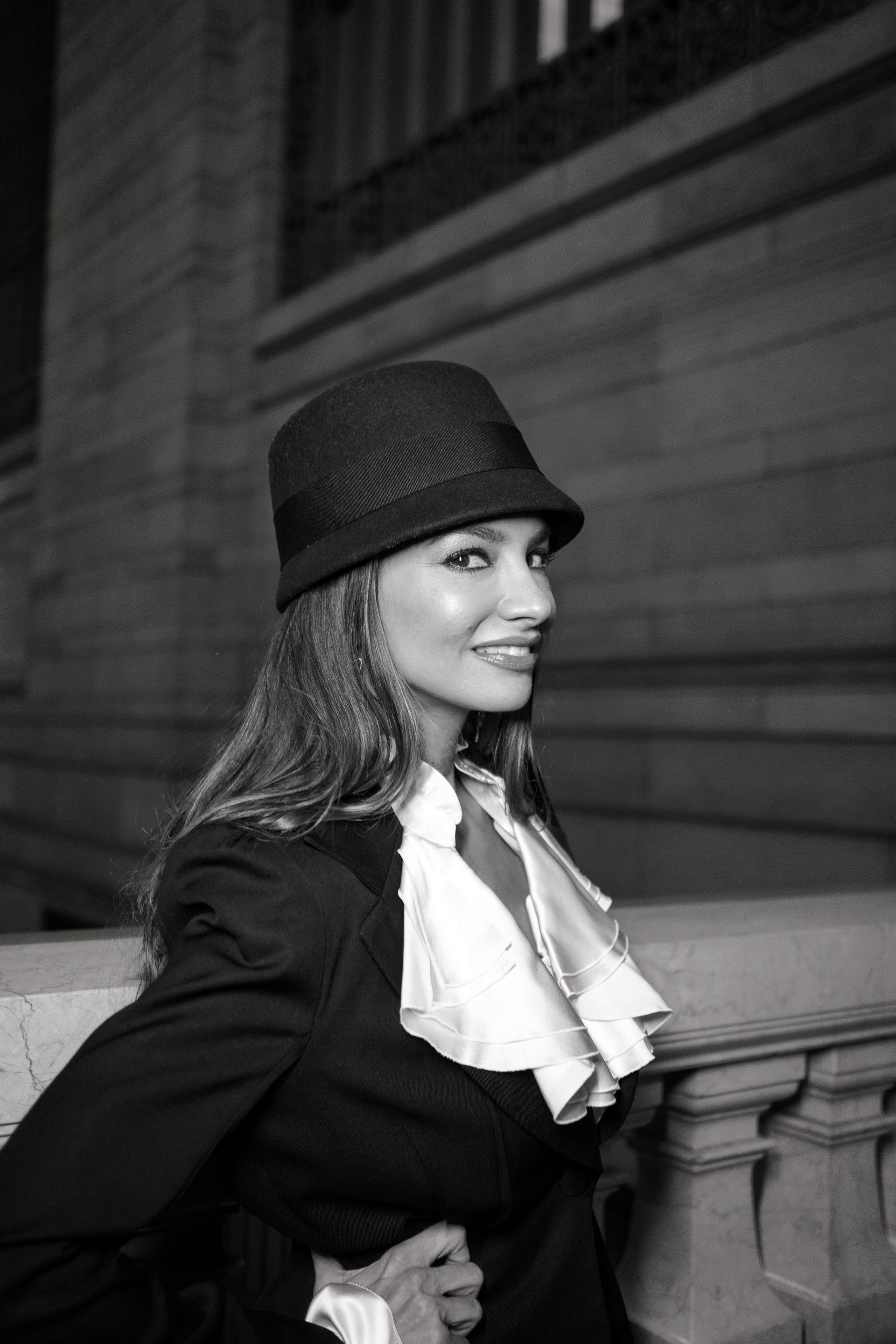 A black and white photo of a woman wearing a hat and a suit.