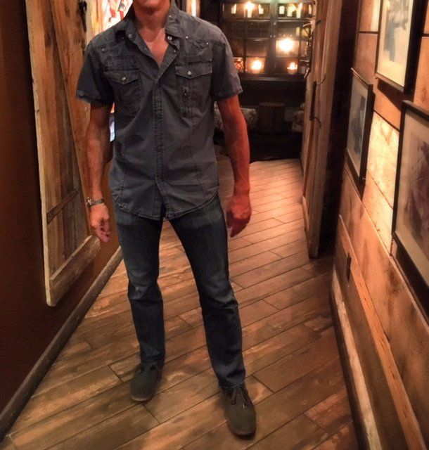 A man in a denim shirt is standing in a hallway