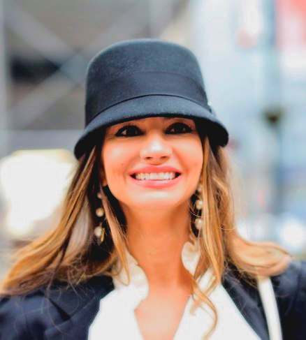 A woman wearing a black hat and earrings is smiling