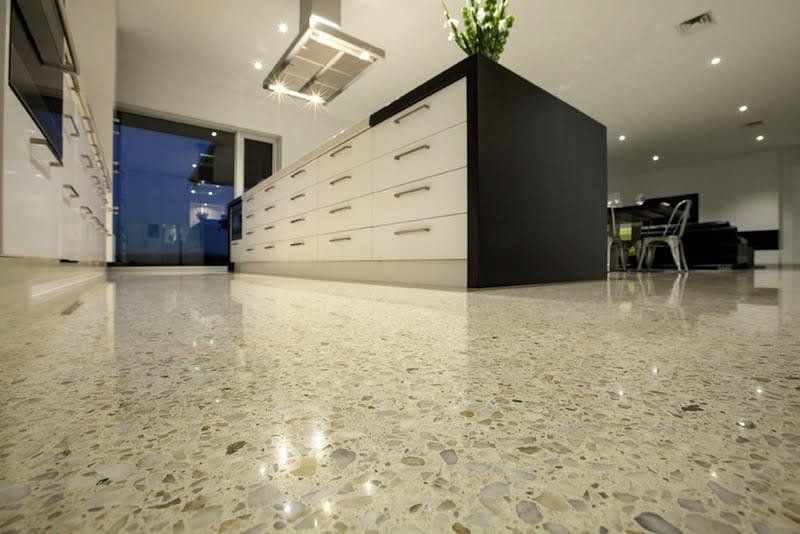 Modern office kitchen with white cabinets, black island, and polished speckled floor