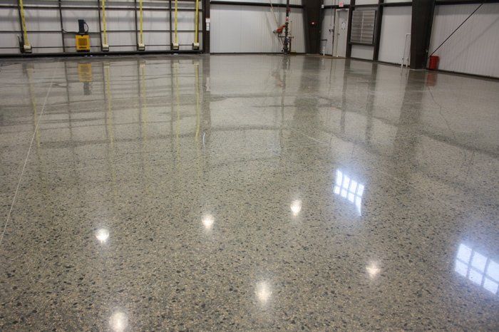Empty polished warehouse floor reflecting lights and garage doors